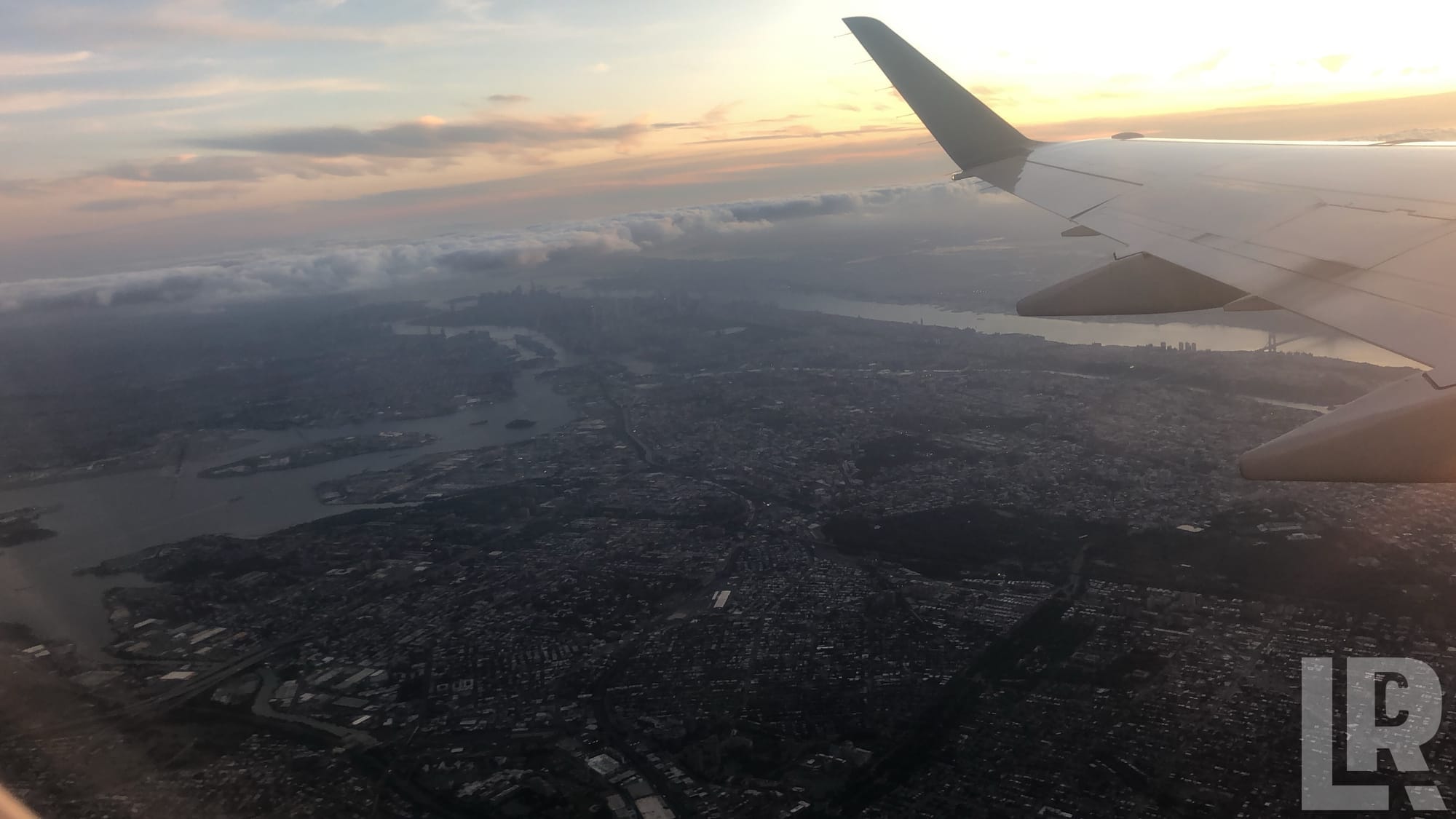 Airplane wing over a sprawling city at sunset viewed from a passenger window seat
