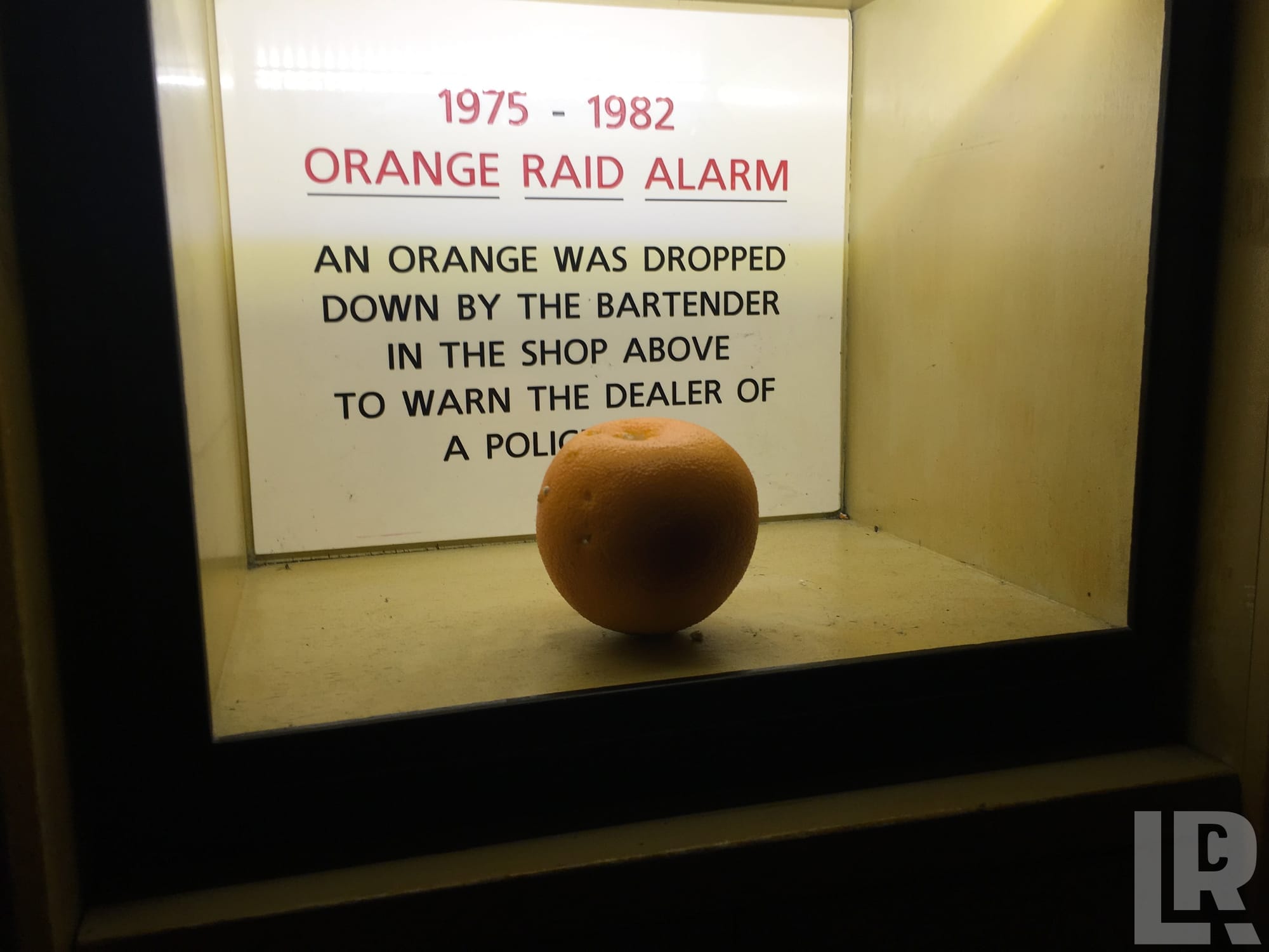 Museum exhibit of an orange labeled as an Orange Raid Alarm used from 1975 to 1982