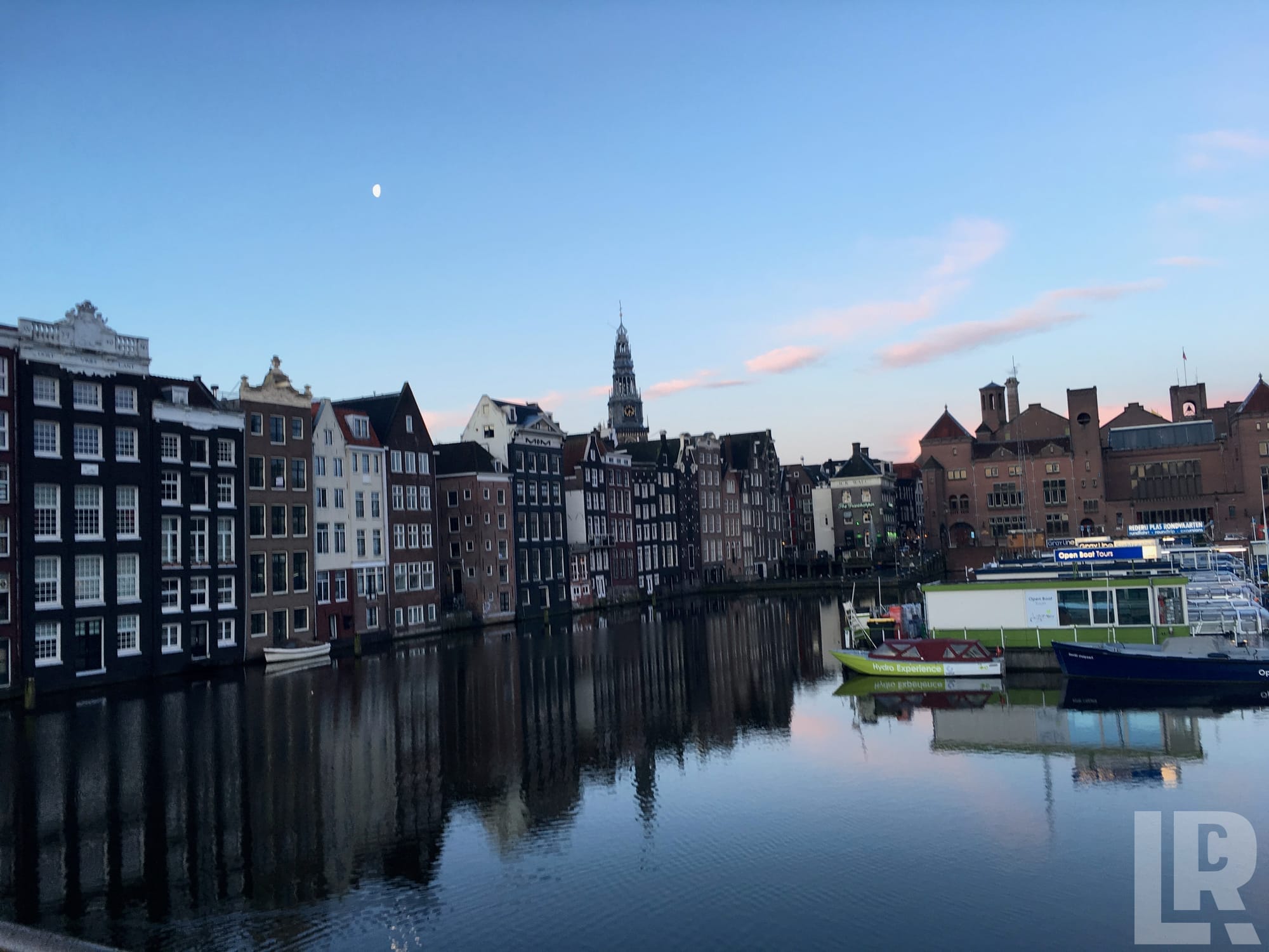 Historic canal houses reflected in still water at dusk with moored boats
