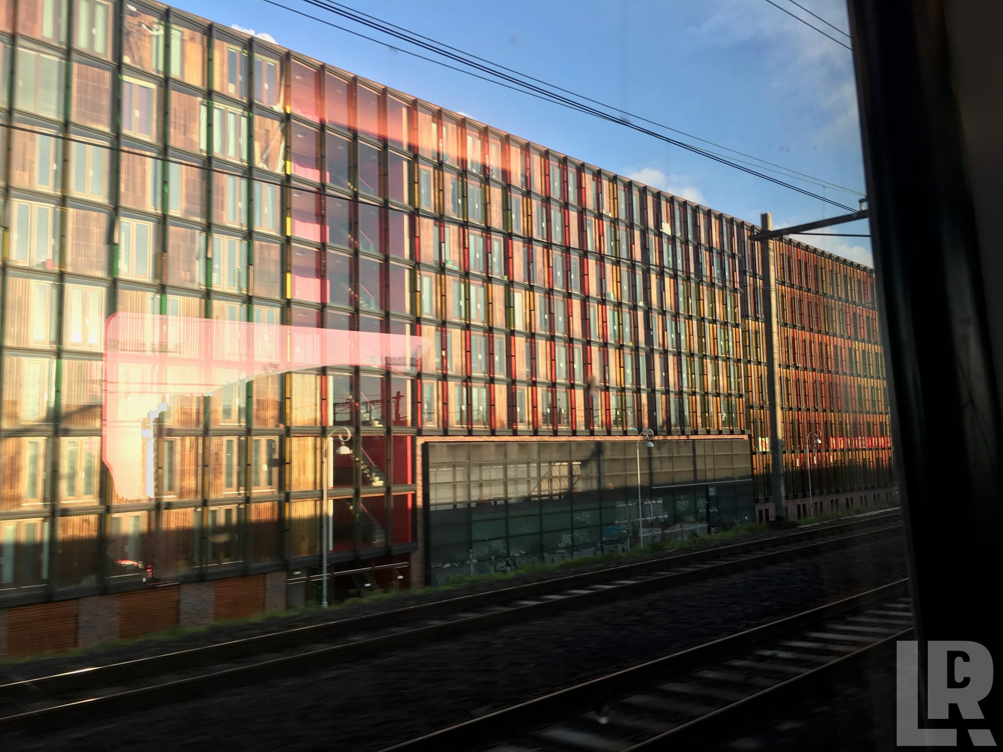 Colorful glass office building seen through a train window with railway tracks below