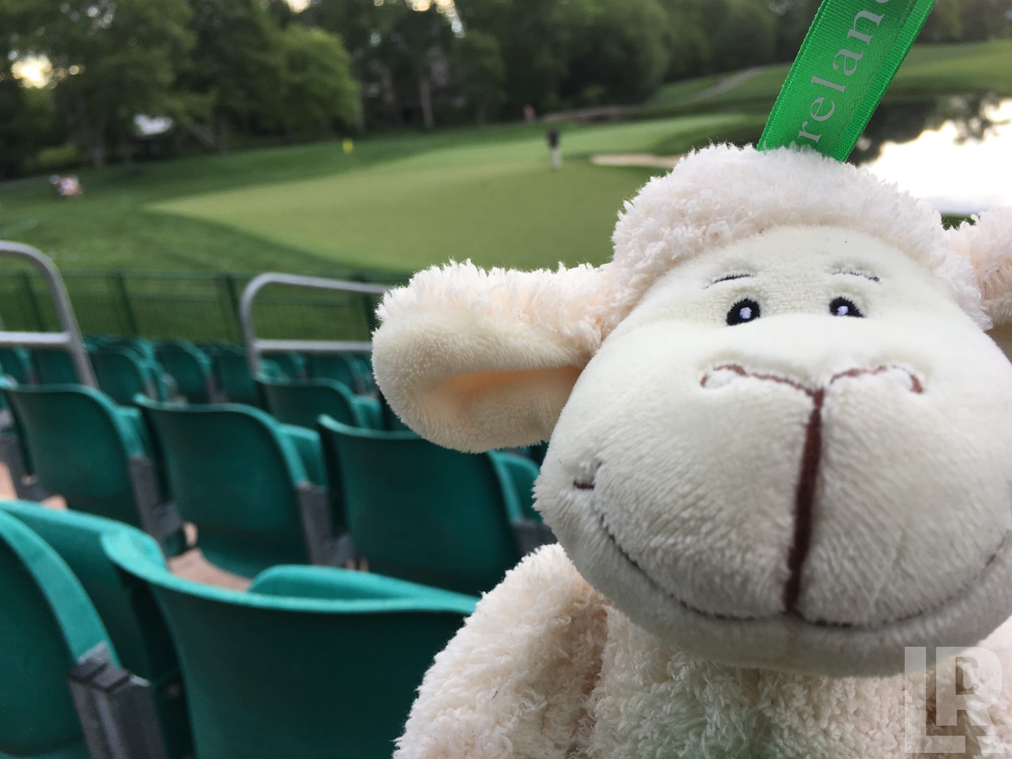 White stuffed lamb toy at a golf course grandstand with green seats