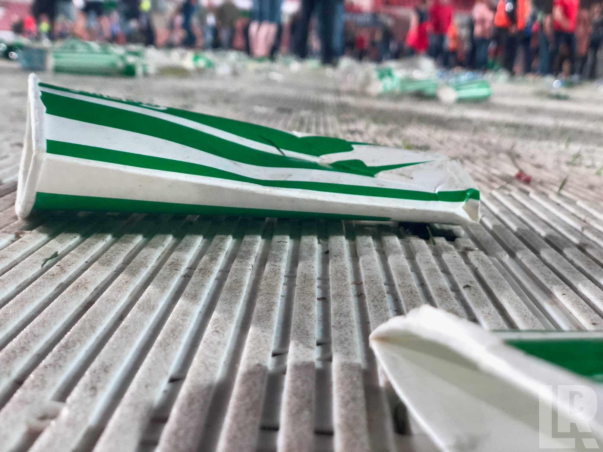 Smashed green and white striped plastic cups scattered on stadium steps