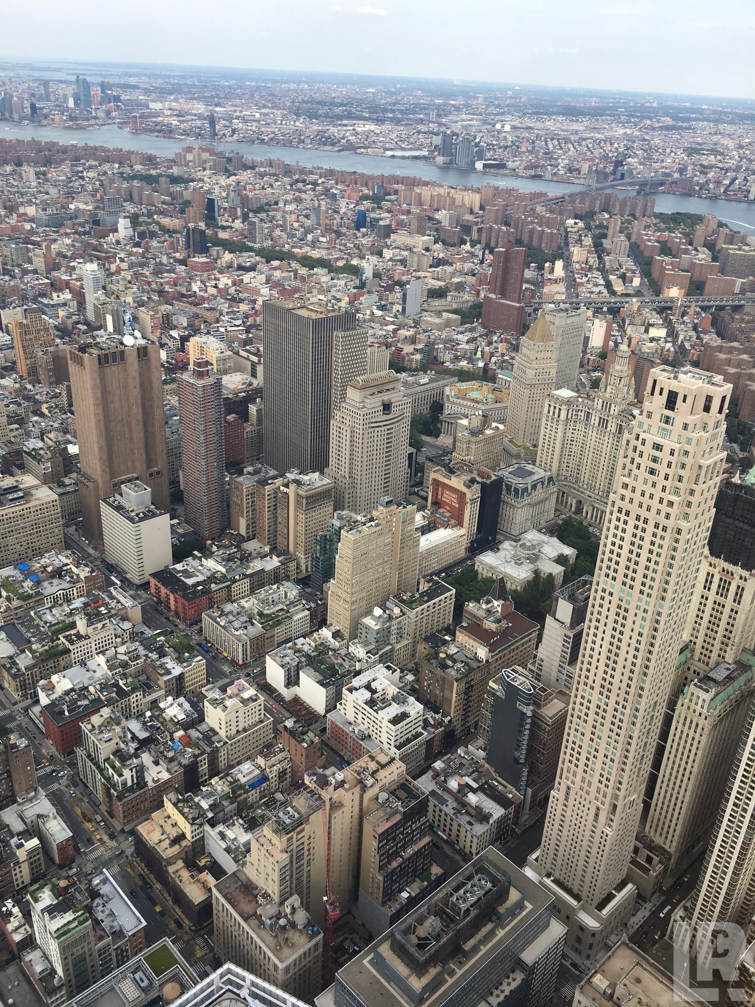 Aerial view of a dense city skyline with tall buildings and a river in the distance