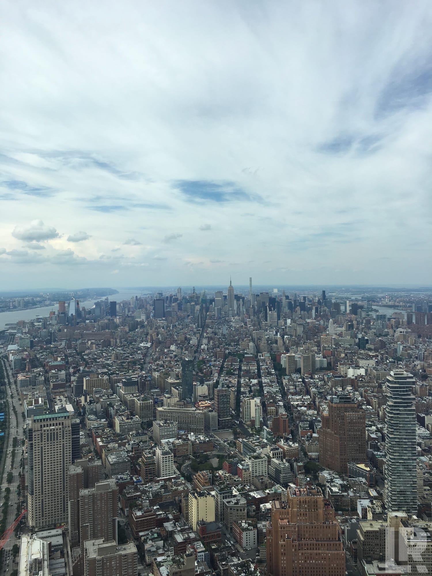 Aerial panoramic view of a large city with skyscrapers and grid streets under a cloudy sky