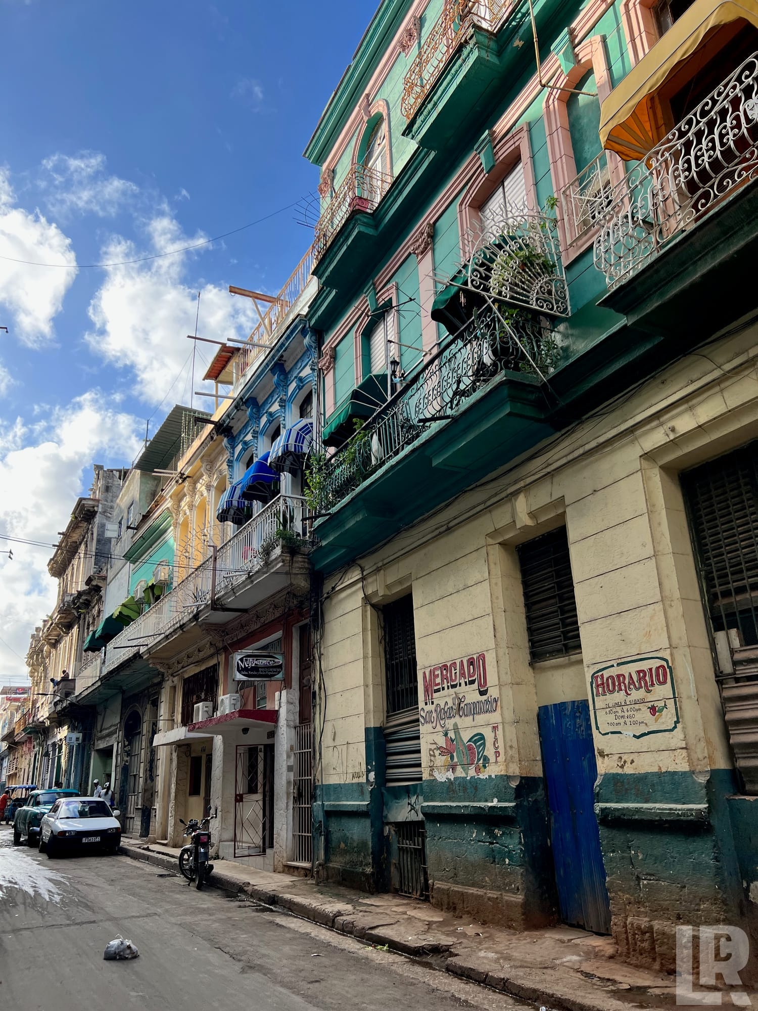 Colorful multi-story colonial buildings with wrought-iron balconies along a narrow city street