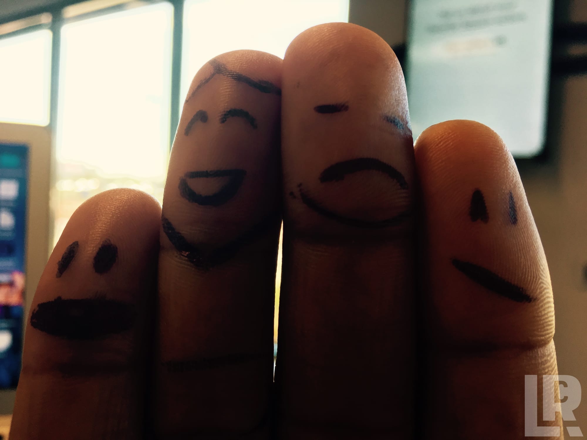 Four fingers with drawn-on facial expressions showing different emotions