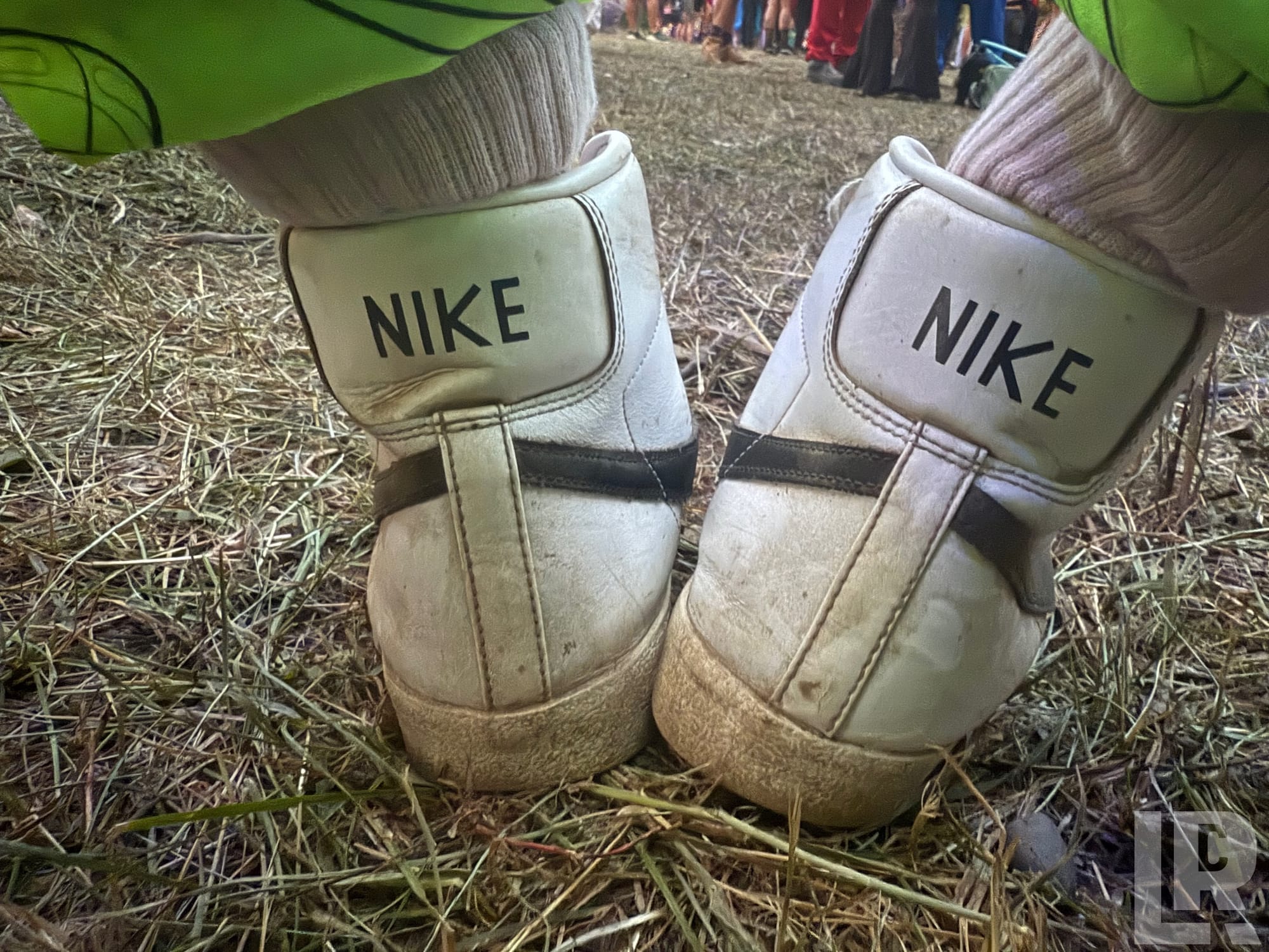 Worn white Nike high-top shoes seen from behind on dry grass