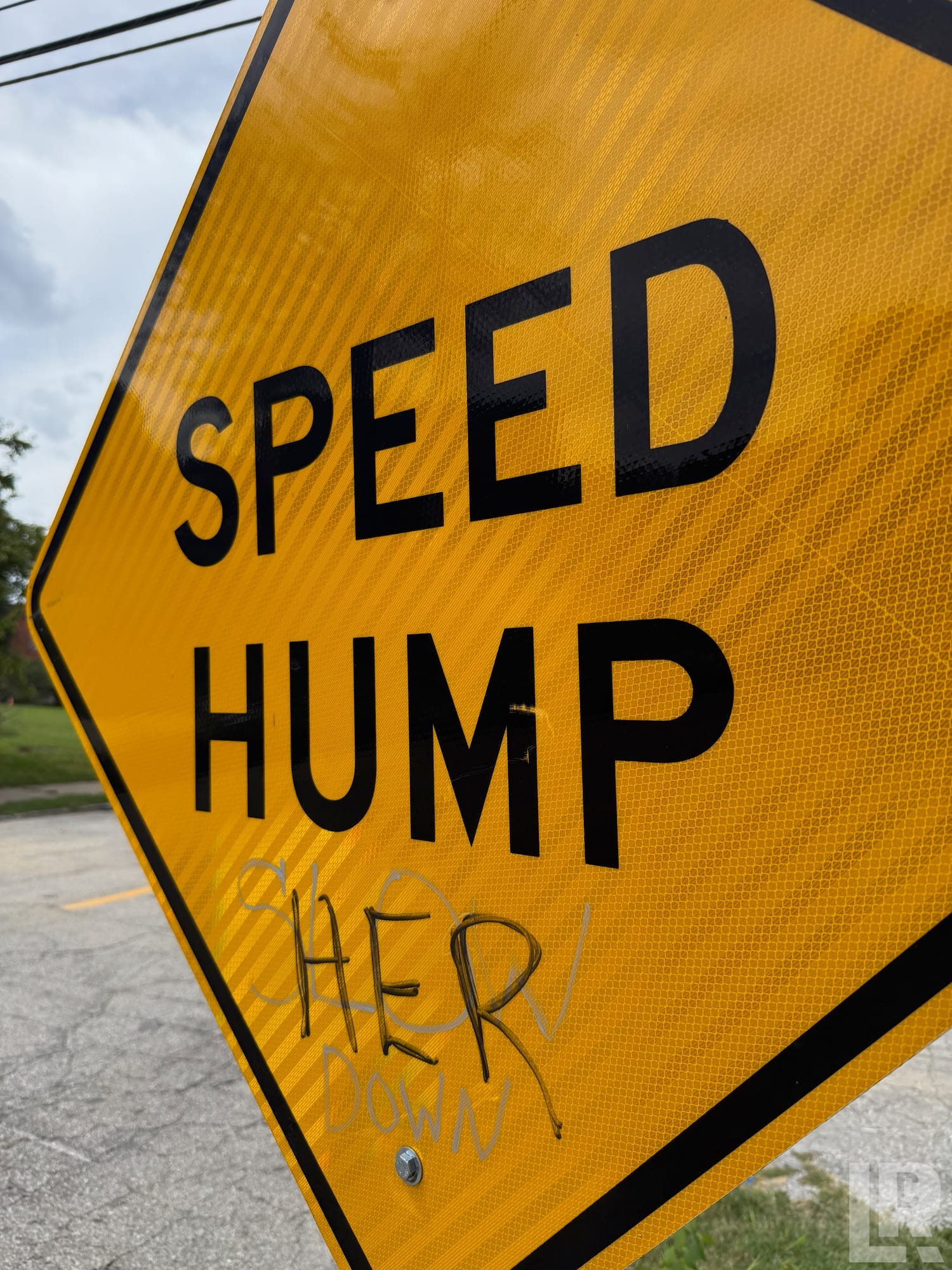 Yellow speed hump road sign with graffiti