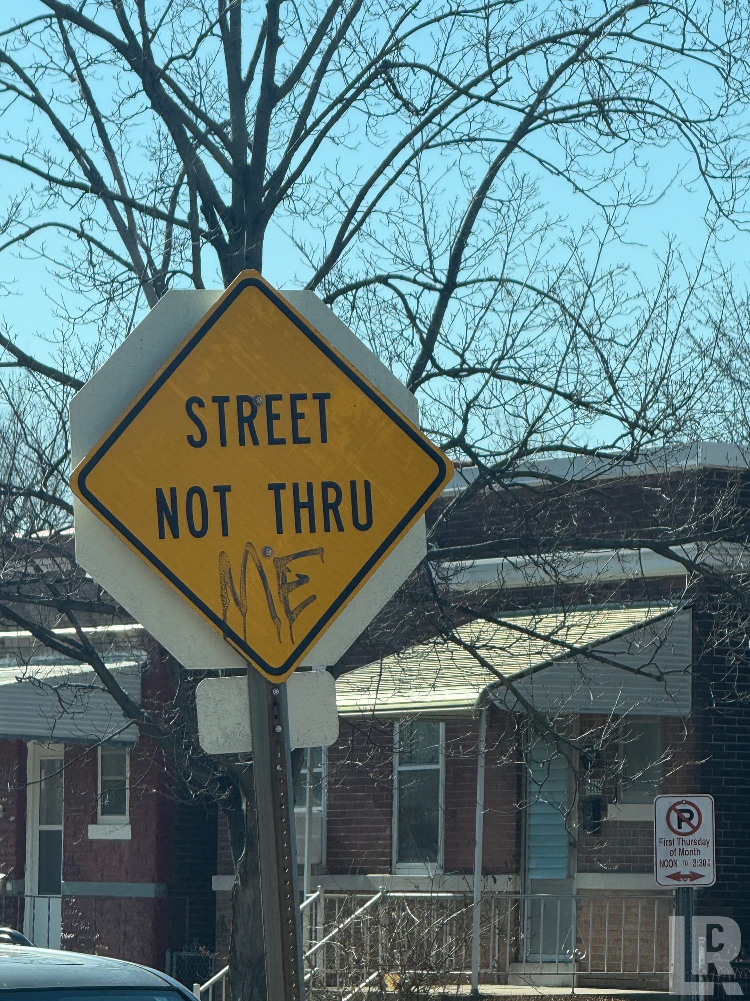 Yellow diamond street sign reading 'Street Not Thru' with graffiti, in a residential area