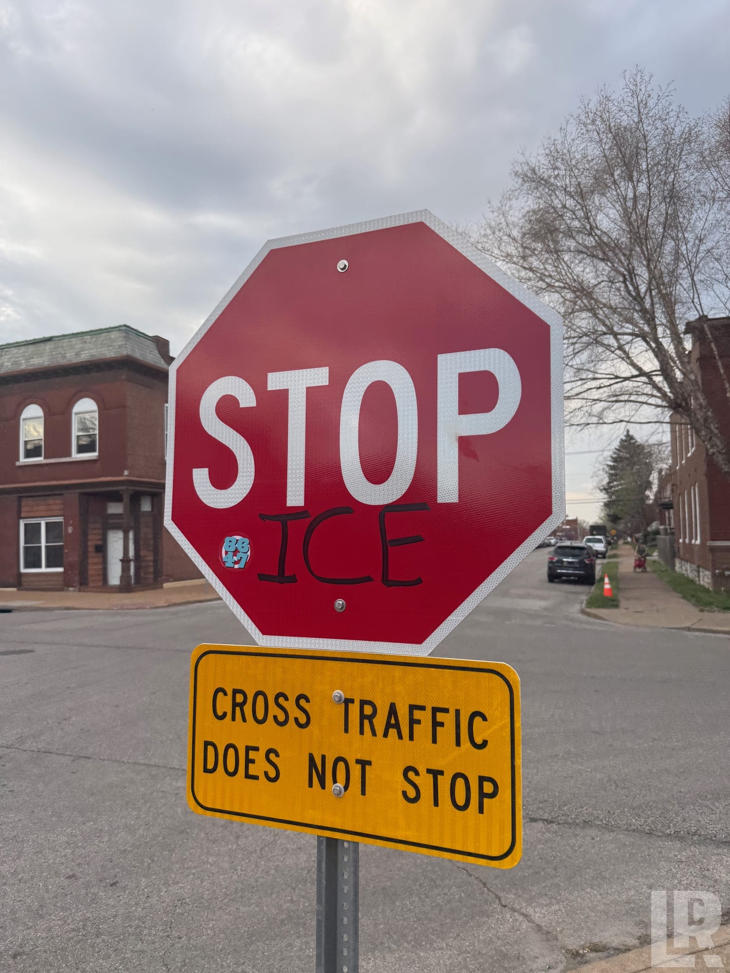 Stop sign vandalized with the word ICE written below STOP, with a cross traffic warning sign beneath