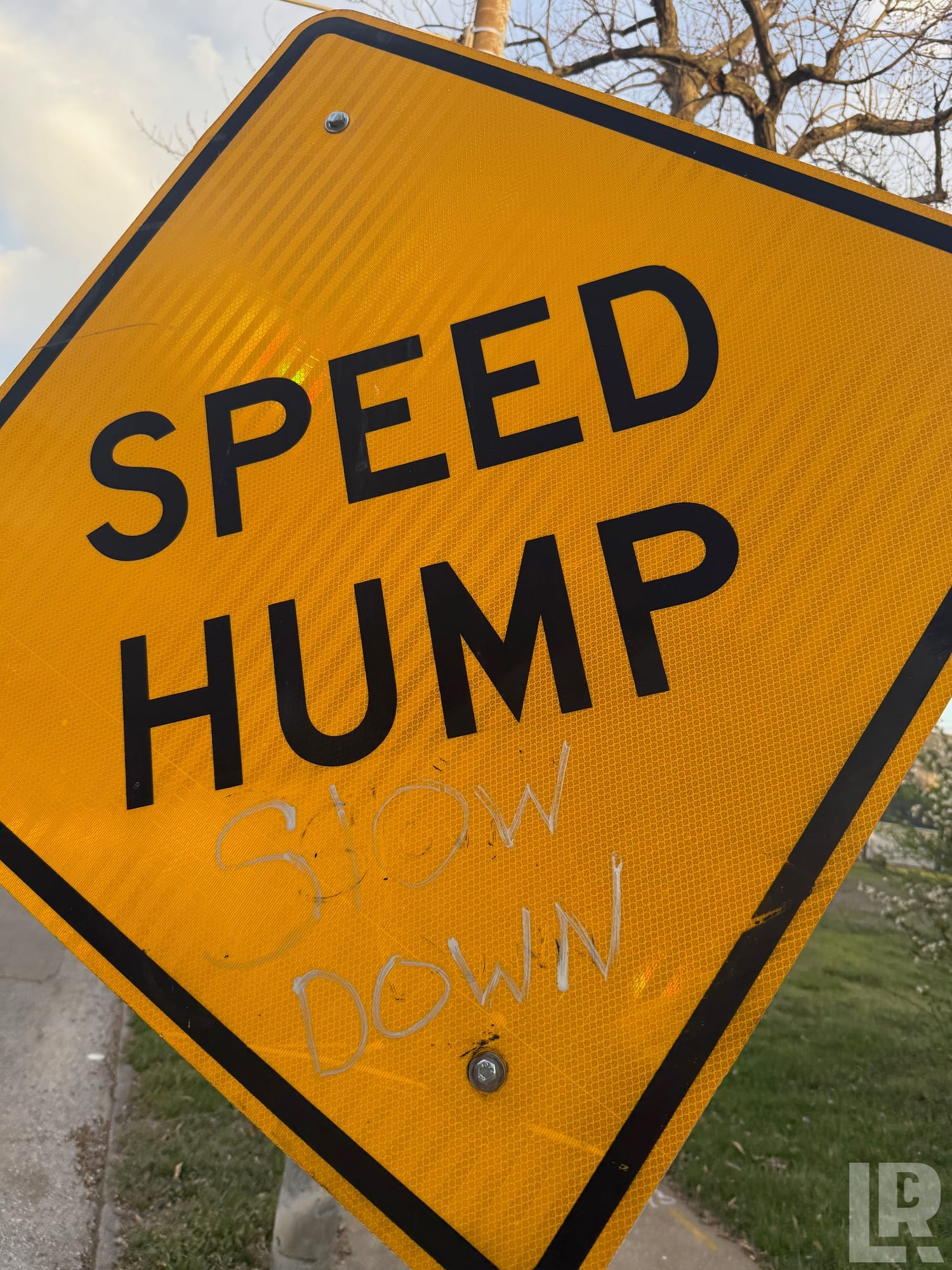 Yellow speed hump road sign with handwritten slow down message added below