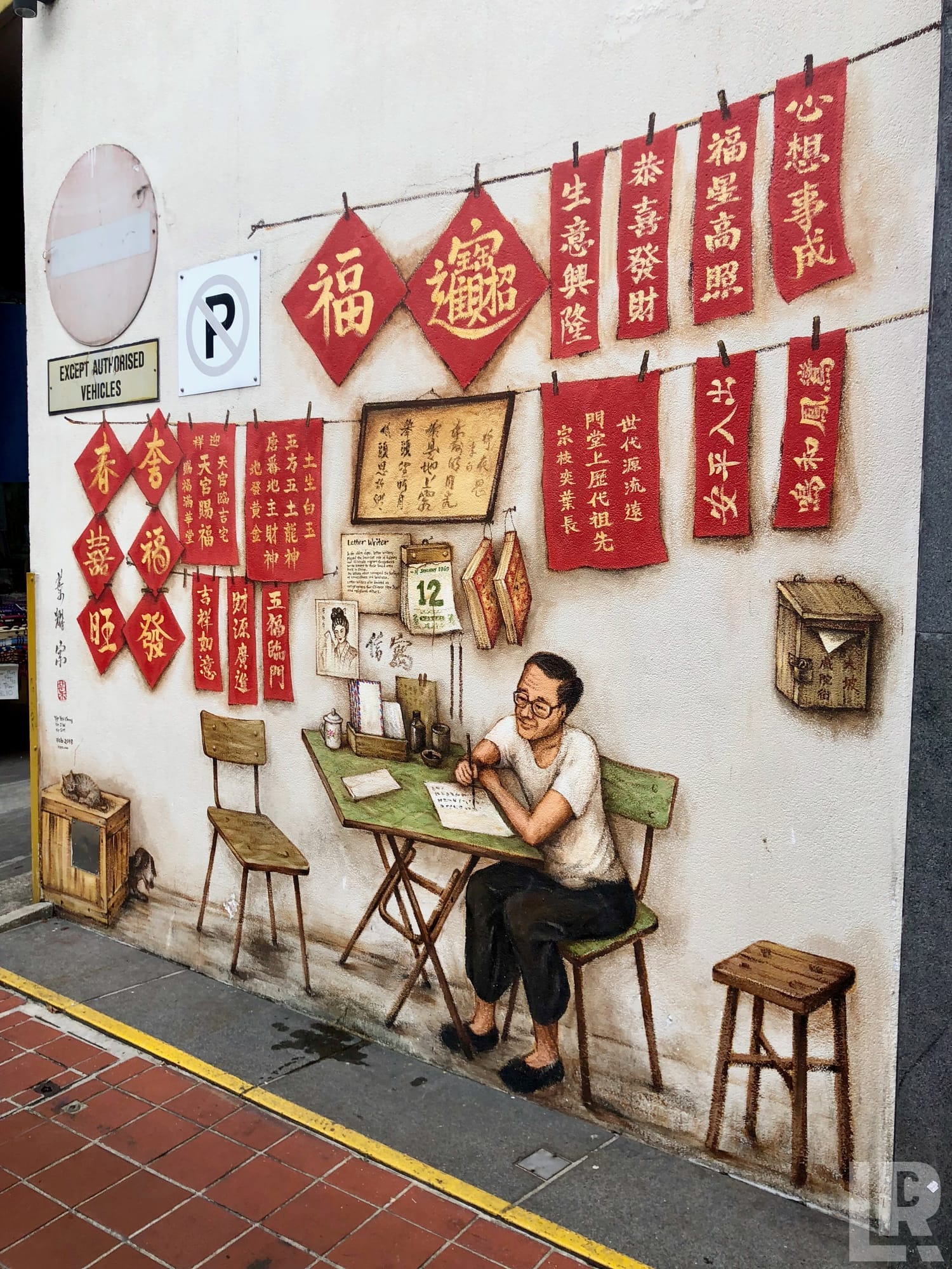 Street mural of a Chinese letter writer at a desk with red calligraphy banners hanging above