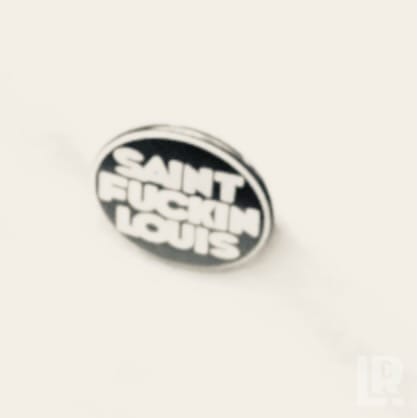 Black oval enamel pin that reads Saint Fuckin Louis in white letters