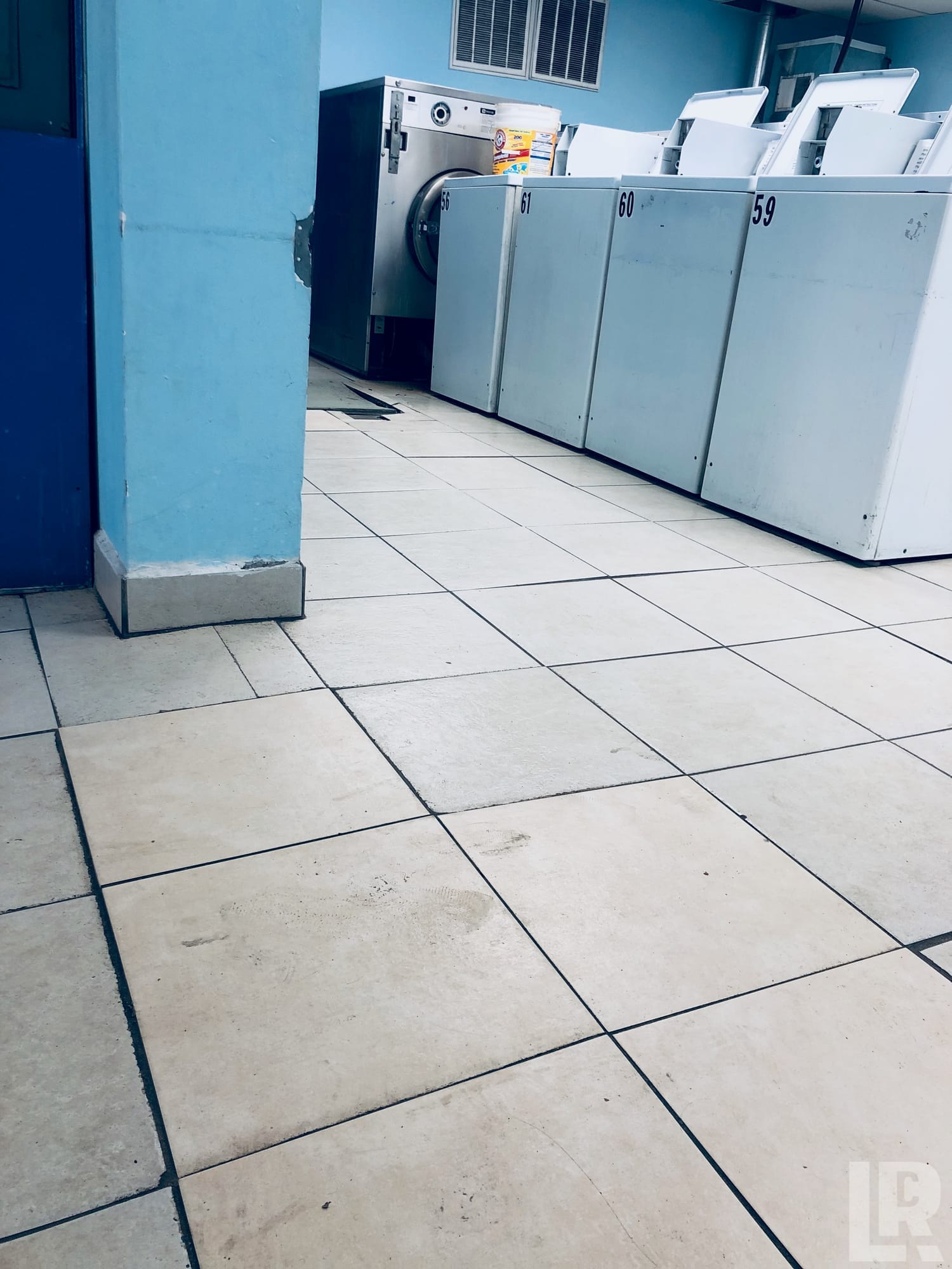 Interior of a laundromat showing numbered top-loading washers along a blue wall