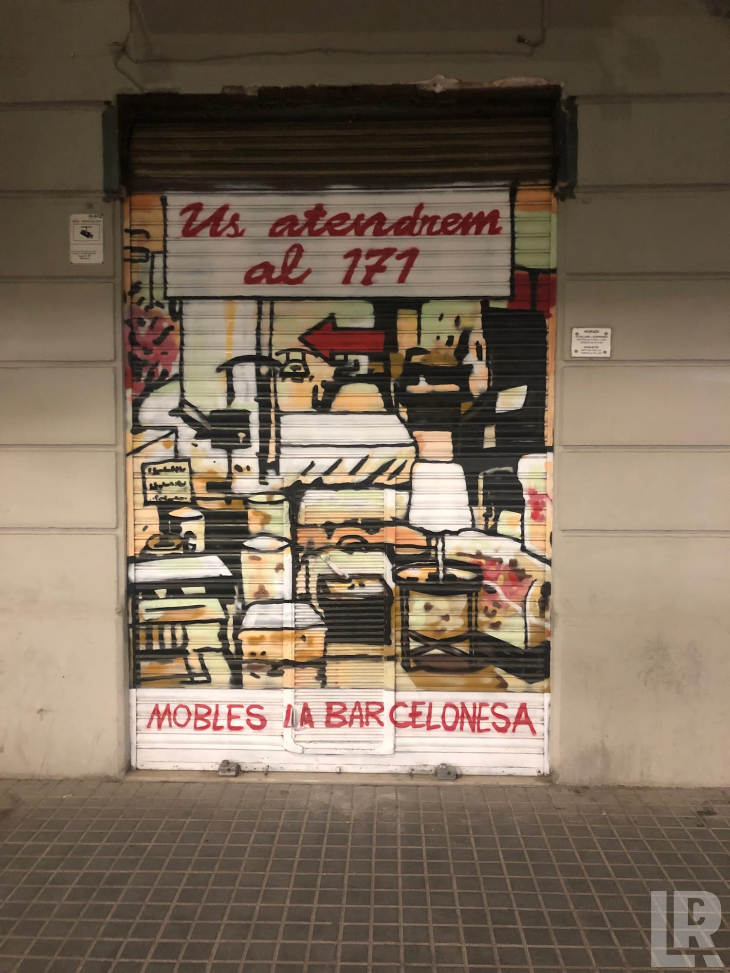 Colorful mural painted on a closed shop shutter advertising a furniture store called Mobles La Barcelonesa