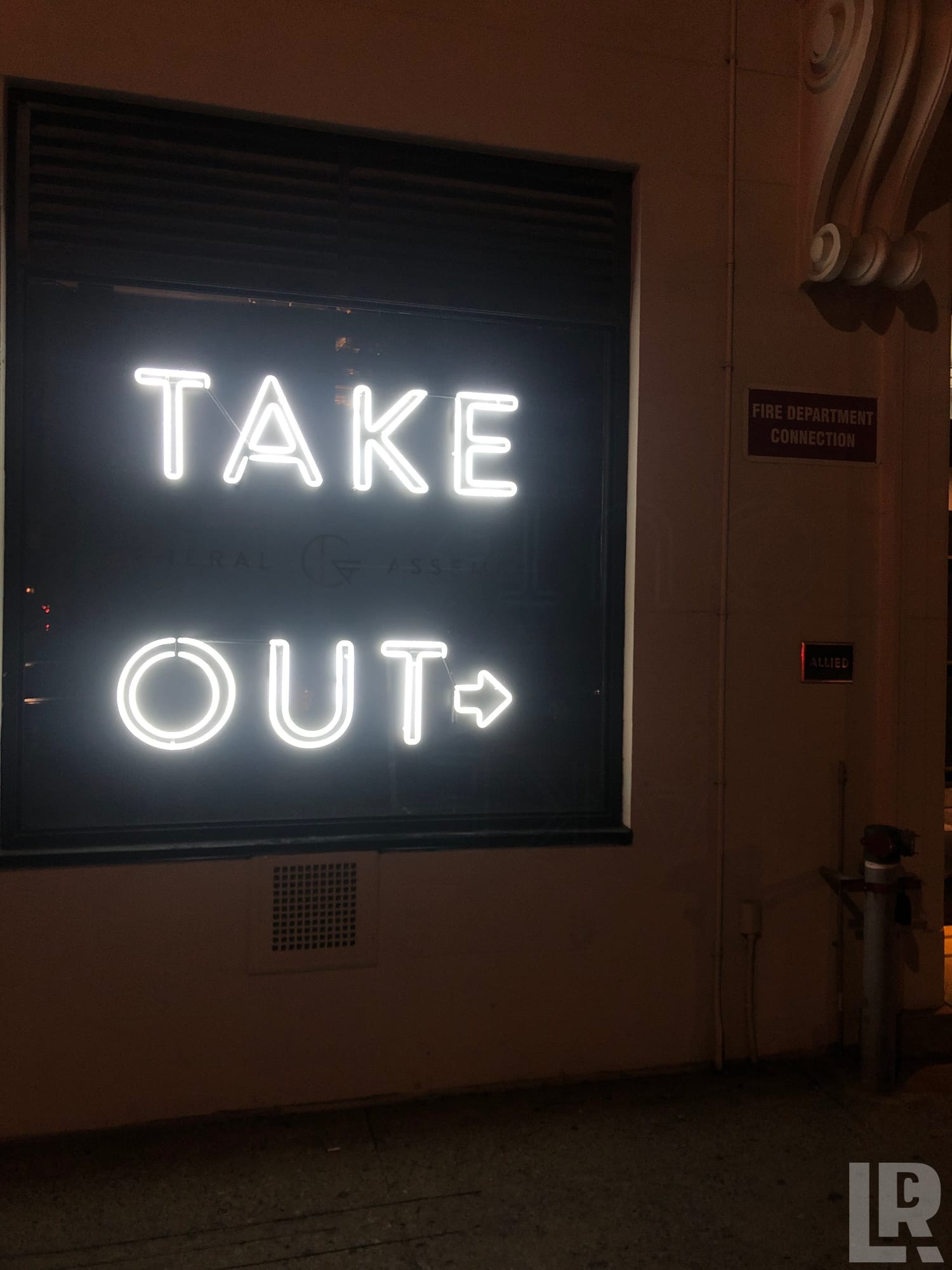 White neon take out sign with arrow in a dark window