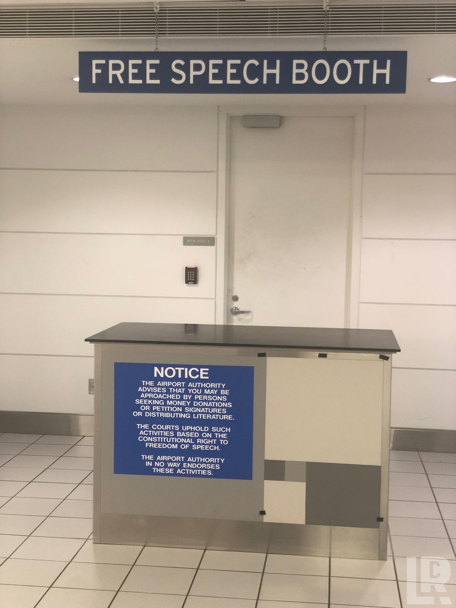 Airport free speech booth with a counter and a blue notice sign about constitutional rights