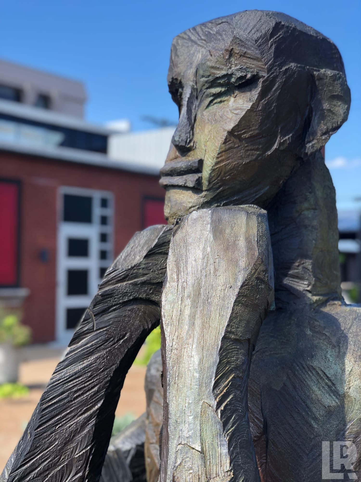 Close-up of an angular dark bronze abstract human sculpture outdoors